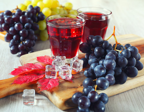 Glasses of grape juice and black and green grapes