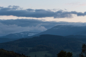 Summer weather phenomenon. Seasonal landscape with morning fog in valley. Clouds drenched valley below the level of the mountain
