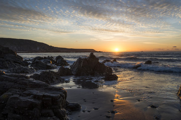 Fototapeta na wymiar Kennack sands beach at sunrise with rocky beach and beautiful cloudy sky, Cornwall, UK