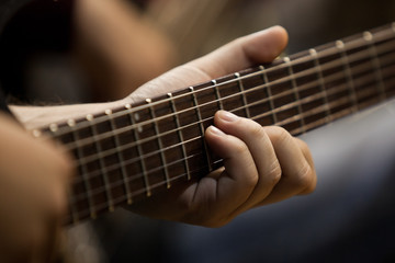 Musician's fingers on the strings of a guitar closeup