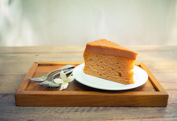 Cake on plate with fork and flower on wood table vintage tone.
