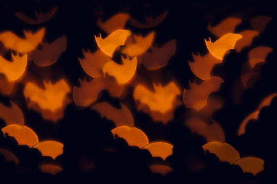 Halloween festive blurred background. Orange bats on a black background.