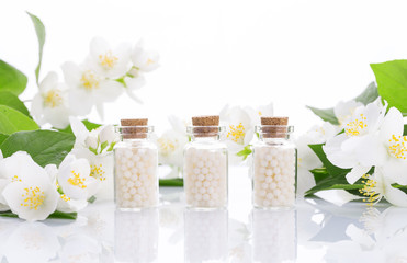 homeopathic pills with spring flowers on white background
