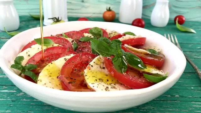 Delicious caprese salad with ripe tomatoes and mozarella cheese with fresh basil leaves. Italian food. Slow motion.