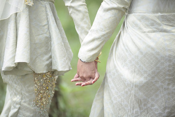 Closeup of a bride and groom holding hands. Shallow DOF.