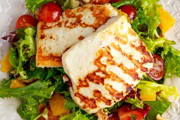 Grilled Halloumi Cheese salad witch orange, tomatoes and lettuce. healthy food