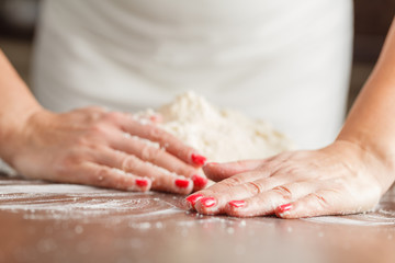 Obraz na płótnie Canvas making raw dough by female hands on table