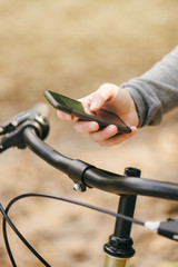 Woman with bicycle using mobile phone outdoors