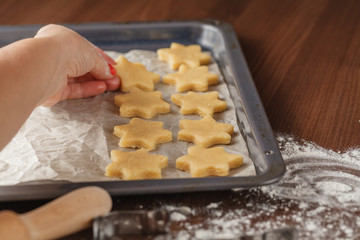 Cookie cutters and shortbread shapes on a board and a baking tra