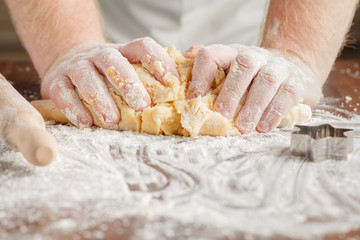 Making dough by mens hands on wooden table background