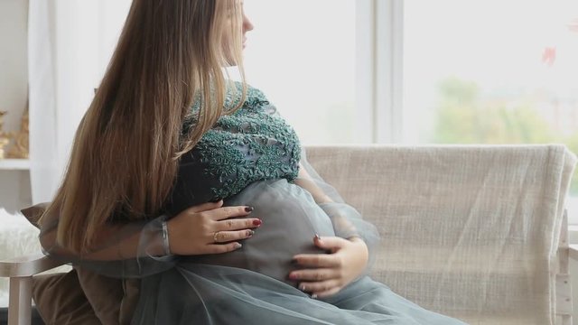 Shot of a pregnant woman holding and touching her stomach.