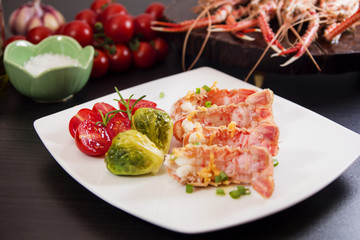 Langoustines or scampi shrimps with garlic olive oil, cherry tomatoes and Brussels sprouts. Selective focus.