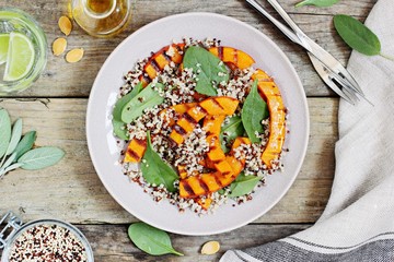Quinoa salad with grilled pumpkin and fresh spinach on a rustic wooden table.Superfood and clean eating concept. Selective focus