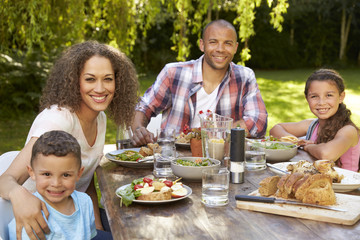 Portrait Of Family At Home Eating Outdoor Meal In Garden