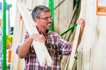 Kunde in der Holzabteilung von Baumarkt sucht Latten für Heimwerker-Projekt