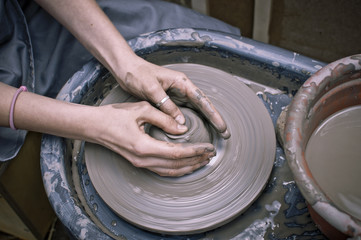 Fototapeta premium Woman's hands making ceramic cup on potter's wheel