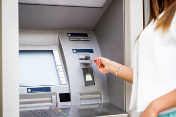 young woman inserting a credit card to ATM