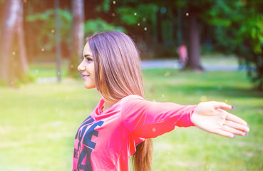 Young woman enjoying sunrise with raised arms in the park