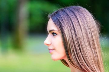 Naklejka premium side view of beautiful young woman portrait with green nature background