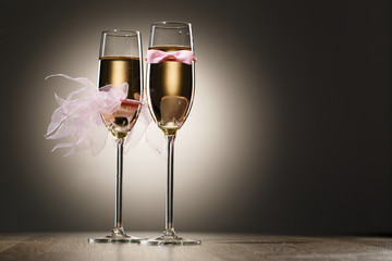 Champagne glasses decorated pink grooms bow-tie and brides veil