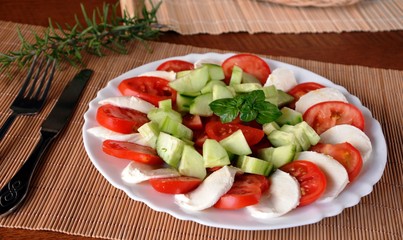 Fresh vegetable salad with mozzarella and basil on a plate