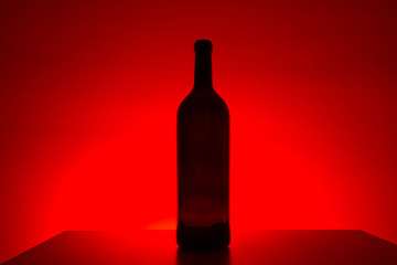Empty bottle on red background on a table, with free space for text
