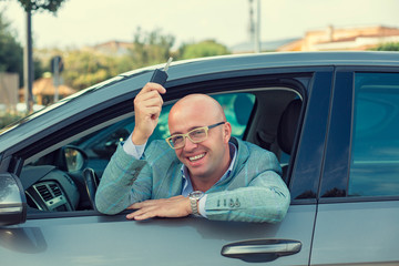 Handsome business man showing keys of his new car. Retro toned p