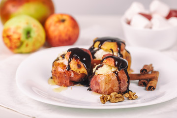 Baked apples on white plate, cinnamon sticks. Healthy eating. Close up.