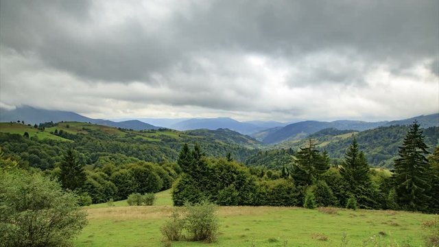 Timelapse of rainy mountain landscape with green spruces on a glade and cloudy sky