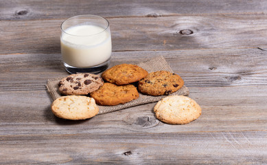 Variety of baked cookies on napkin and glass of milk