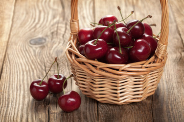 Fototapeta na wymiar Ripe cherries in a basket on an old board