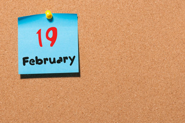 February 19th. Day 19 of month, calendar on cork notice board background. Winter time. Empty space for text