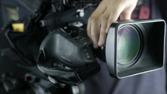 Camera operator working with a cinema broadcast camera at the unrecognizable tv news studio. 4K.