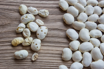 White beans, lots of beans on the wooden table. Wormy beans