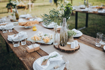 The composition of flowers and greenery standing on served table in the area of wedding party