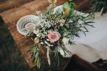 The composition of flowers and greenery is on a festive table in the area of wedding party