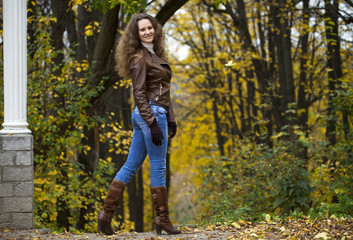 Autumn fashion image of young woman walking in the park