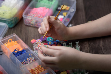 children's hands are weaving figures out of colored rubbers