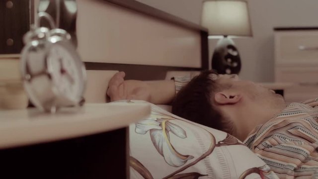 Close-up of young man is sleeping calmly and suddenly has a bad dream