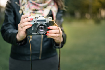 Woman hand holding retro camera close-up on background of autumn