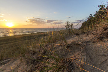 Summer Beach Sunset Horizon. Sunset on the horizon of a wide sandy beach with a sand dune and dune grass in the foreground. Hoffmaster State Park. Michigan.