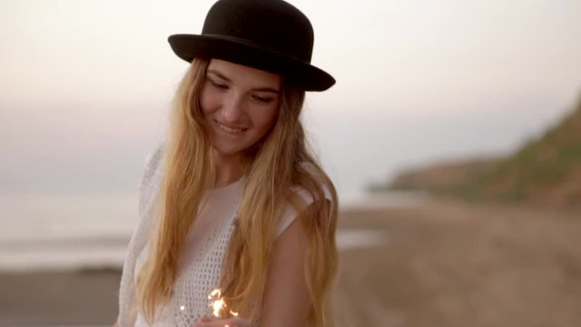 Teenage beautiful girl with sparklers on the beach at sunset HD slow motion