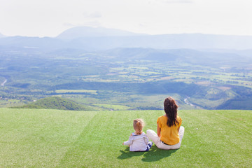 Mutter sitzt mit der Tochter auf einem Berg