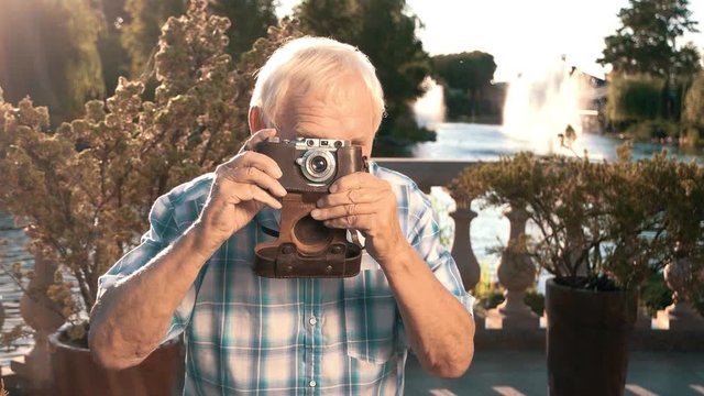 Senior male holding camera. Elderly man outdoor. Photographs of nature in summer. Wonderful life around us.