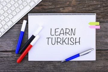 Notebook with LEARN TURKISH Handwritten on wooden background