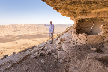 Man showing pointing desert crater moutains landscape. © subbotsky