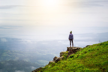 yong woman standing on the top of the mountain observing nature