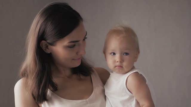 Young Happy Mother Holding her Newborn Child. Family at home. Beautiful smiling Mom and Happy Baby Together.