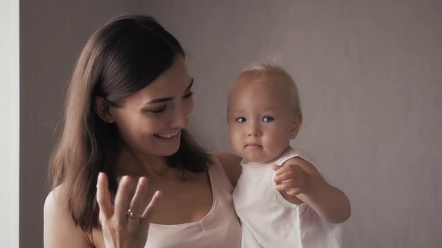 Young Happy Mother Holding her Newborn Child. Family at home. Beautiful smiling Mom and Happy Baby Together.