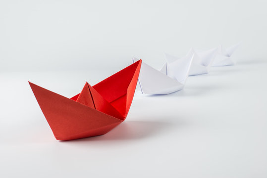 red paper ship leading among white
